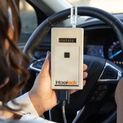 Woman holding an intoxalock ignition interlock device for to prevent drinking and driving